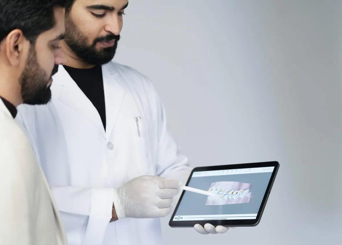 An orthodontist reviewing a 3D treatment plan on a tablet with a colleague